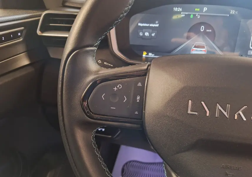 Gros plan sur le volant noir du LYNK & CO 01 2023 avec commandes intégrées et affichage numérique du régulateur adaptatif.