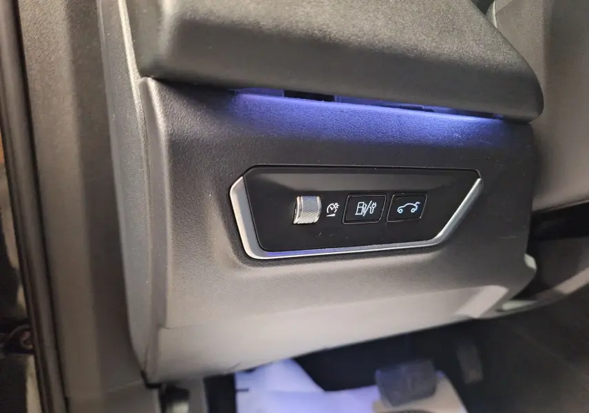Détail des commandes sous le tableau de bord côté conducteur du Lynk & Co 01 noir avec éclairage bleu.