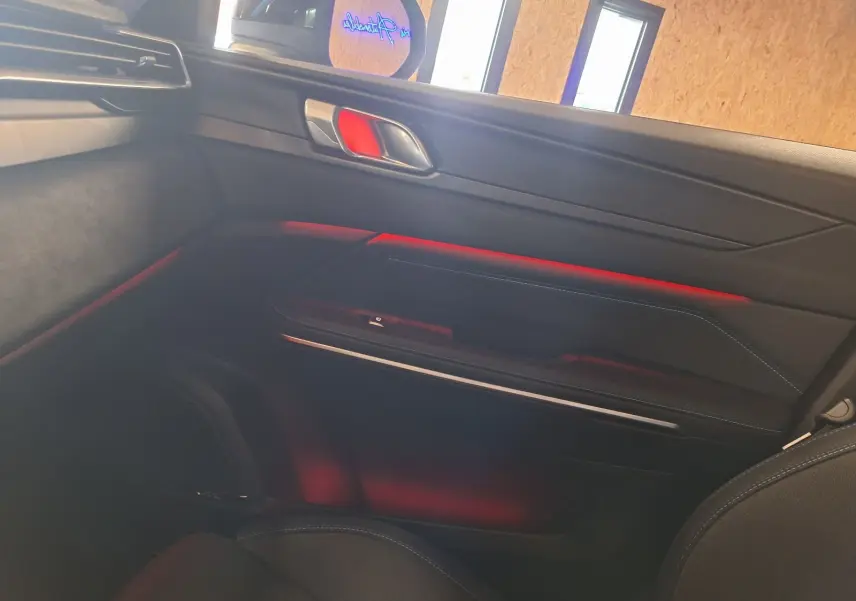 Intérieur côté droit du LYNK & CO 01 noir 2023, avec éclairage d'ambiance rouge et garnitures modernes.