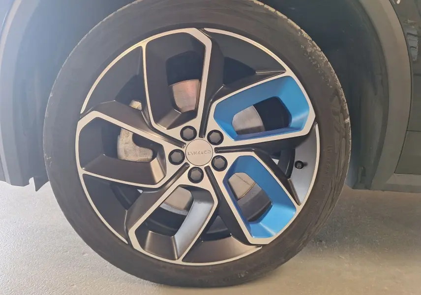 Gros plan sur la jante bi-ton noire et bleue du LYNK & CO 01 hybride rechargeable noir, mettant en valeur son design moderne.