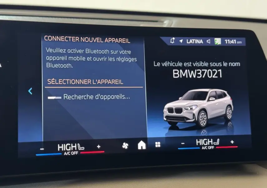 Affichage digital intérieur montrant une BMW X1 gris clair en 3/4 avant sur écran tactile du tableau de bord.