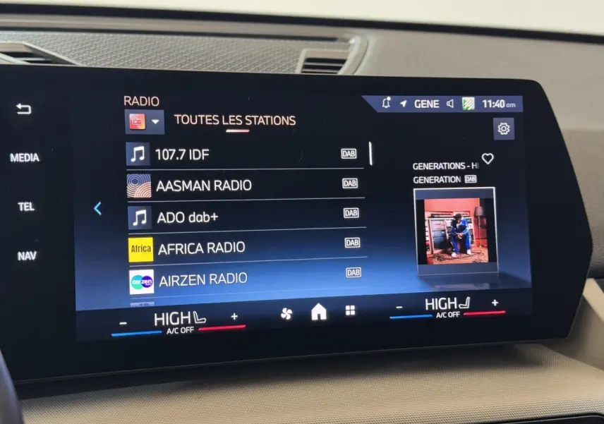 Écran tactile central affichant les stations radio dans l’habitacle beige d’une BMW X1 gris foncé, vue de face.