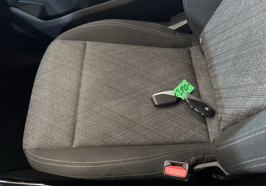 Gros plan sur le siège avant droit gris foncé du BMW X1 2024 avec clé et ceinture de sécurité visible.