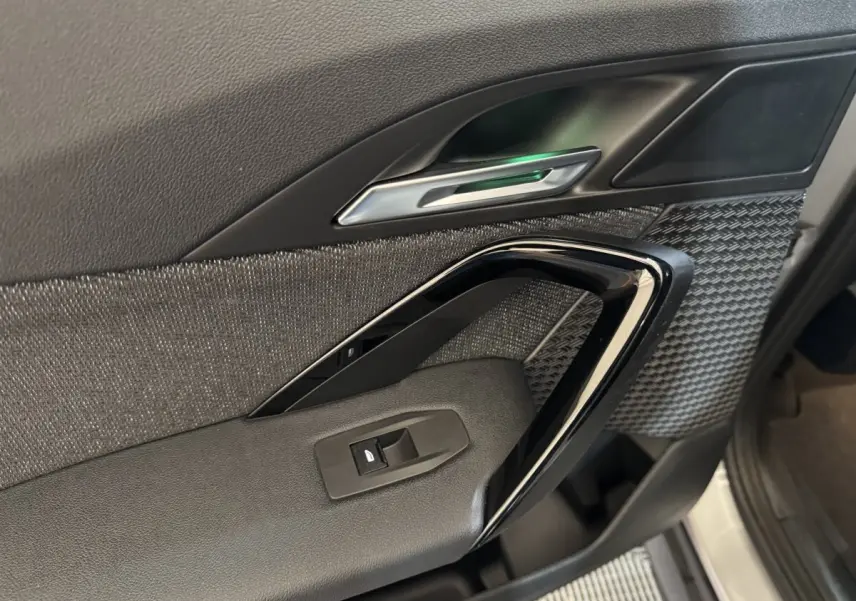 Détail de la porte intérieure côté conducteur du BMW X1 2024, avec garniture noire texturée et poignée argentée.
