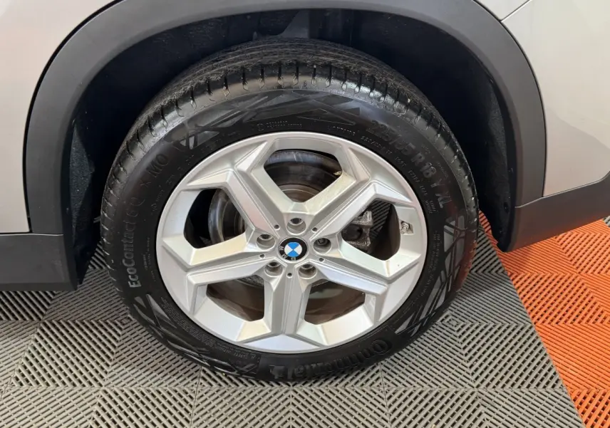 Gros plan sur la roue avant droite avec jante argentée du BMW X1 gris foncé 2024 sDrive20i Business Design.