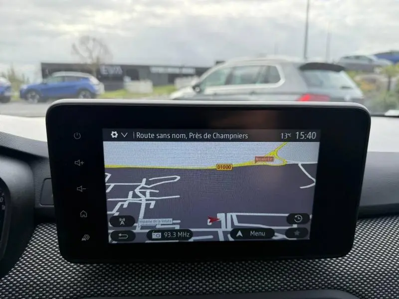 Vue intérieure centrée sur l’écran tactile du GPS du Dacia Jogger 2025, avec tableau de bord et extérieur flou visible.