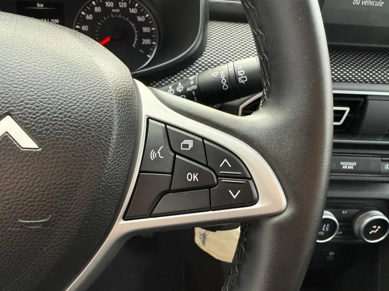 Gros plan sur les commandes au volant côté droit du Dacia Jogger gris Schiste métallisé, tableau de bord en arrière-plan.