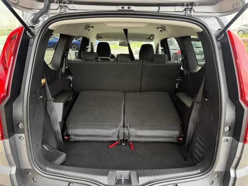 Vue arrière du coffre du Dacia Jogger gris schiste métallisé 2025 avec banquette arrière rabattue et espace de chargement visible.