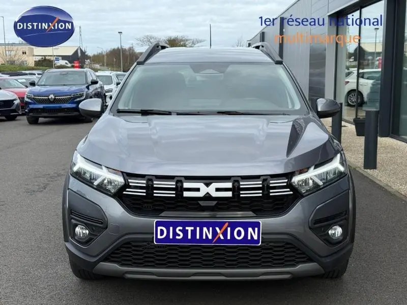 Vue frontale d'un Dacia Jogger 2025 gris schiste métallisé avec calandre noire et phares LED allumés.