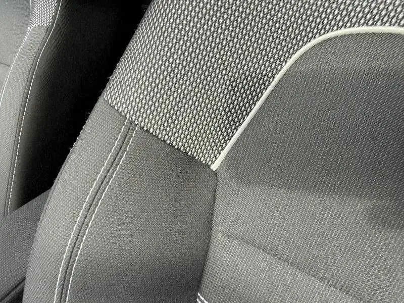 Gros plan sur le tissu gris et noir des sièges avant du Dacia Jogger 2025, soulignant les finitions en surpiqûres blanches.