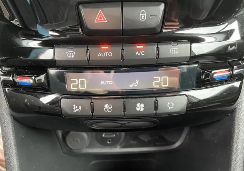 Gros plan sur la console centrale noire brillante du Peugeot 2008, affichant la climatisation automatique bizone réglée à 20°C.