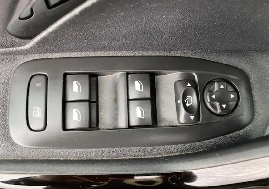 Gros plan sur les commandes des vitres et rétroviseurs côté conducteur d'une Peugeot 2008 gris platinium.