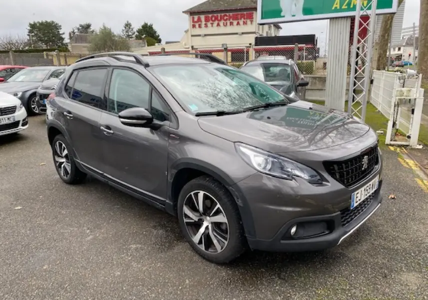 Peugeot 2008 gris platinium en 3/4 avant droit, avec jantes alliage noires diamantées et barres de toit noir brillant.