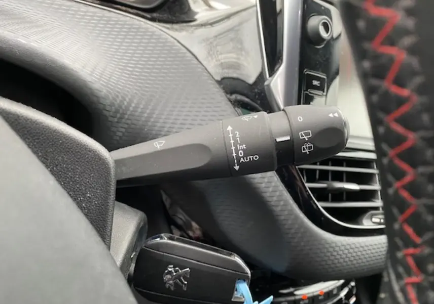 Gros plan sur la commande d'essuie-glace à gauche du volant dans l'habitacle du Peugeot 2008 gris platinium.