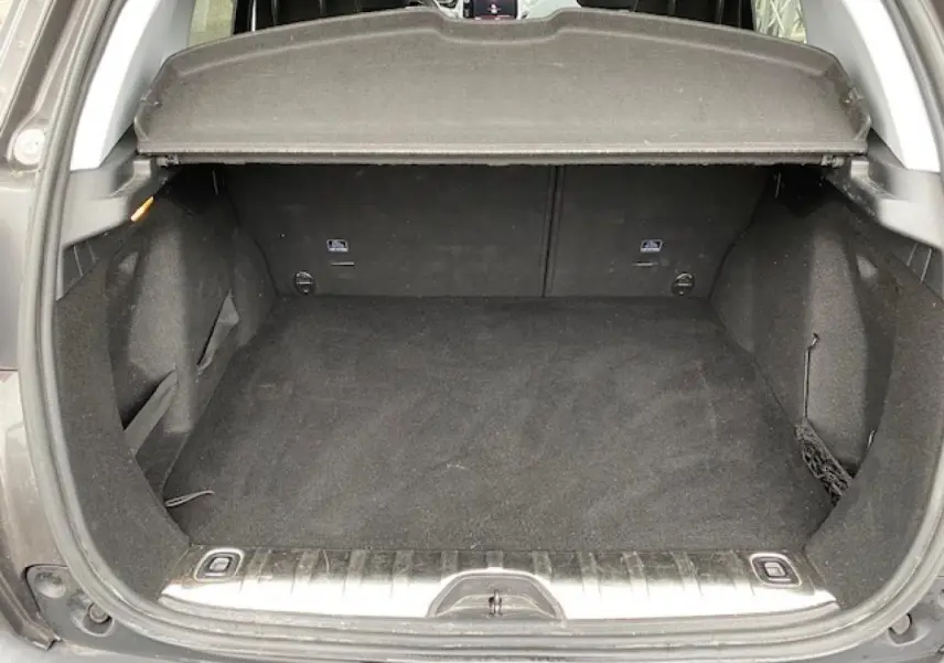 Coffre ouvert vu de l'arrière d'un Peugeot 2008 gris platinium, montrant un espace de chargement propre et spacieux.