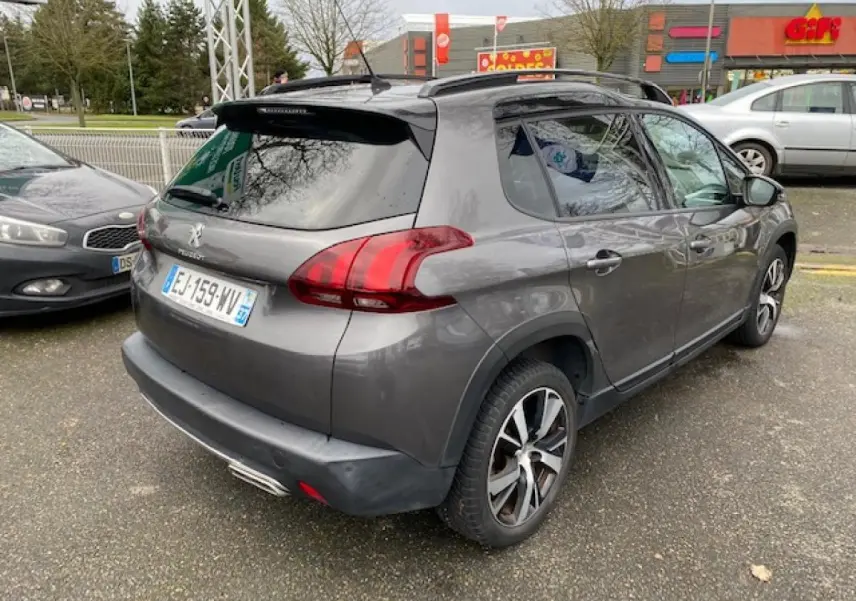 Peugeot 2008 gris platinium en 3/4 arrière droit, avec barres de toit noir brillant et jantes alliage 17 pouces.