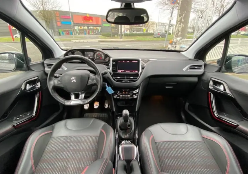 Vue intérieure frontale du Peugeot 2008 GT Line 2017, montrant le volant, tableau de bord et sièges noirs avec surpiqûres rouges.