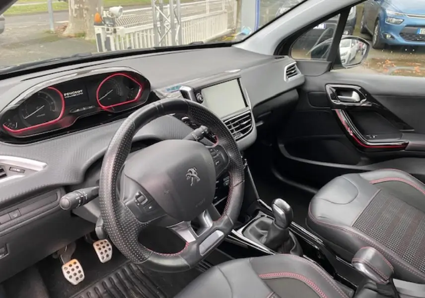 Vue intérieure côté conducteur du Peugeot 2008 GT Line 2017, volant cuir noir perforé avec surpiqûres rouges et pédalier aluminium sport.