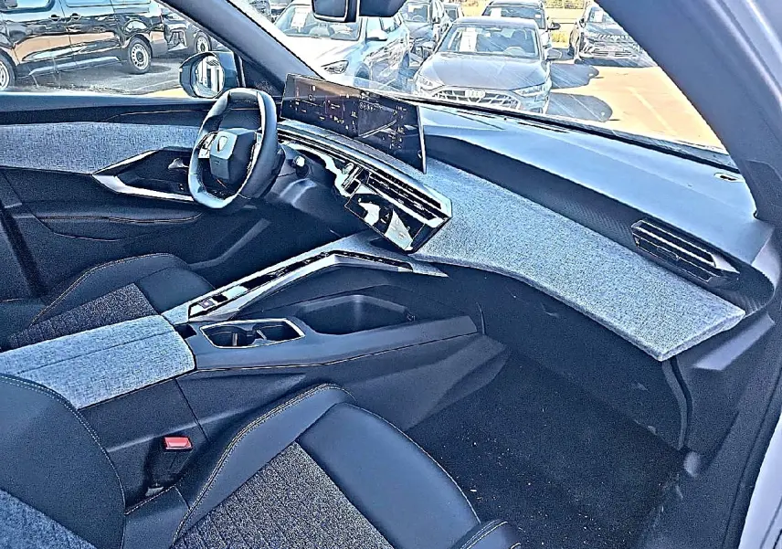 Vue intérieure côté passager du Peugeot 5008 Hybrid 145 allure e-dcs6 2025, tableau de bord et sièges en tissu bleu et cuir noir.