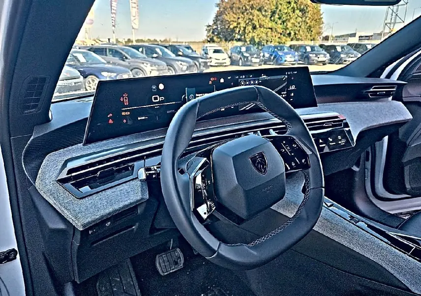 Vue intérieure côté conducteur du Peugeot 5008 Hybrid blanc, avec volant compact et tableau de bord numérique large.