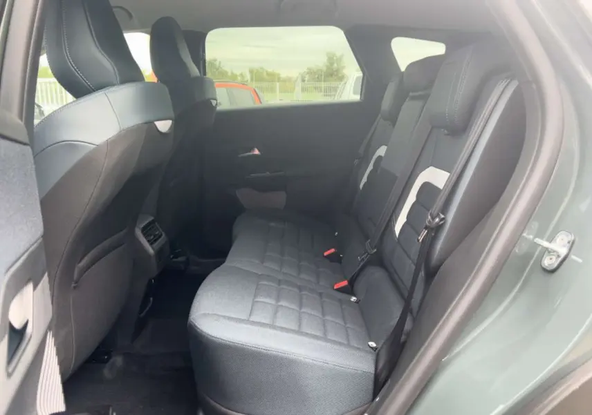 Vue côté gauche sur l'intérieur arrière du Citroën C5 Aircross Hybrid 145 Plus PK Drive vert Astoria avec sièges tissu gris.