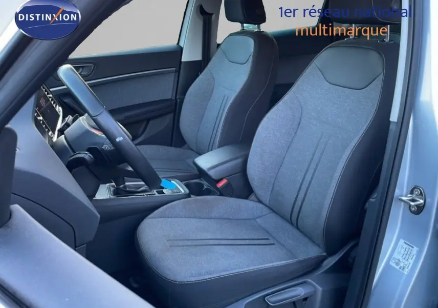 Vue intérieure côté conducteur du SEAT Ateca 2022 argent, sièges tissu gris avec contours noirs et volant multifonction.