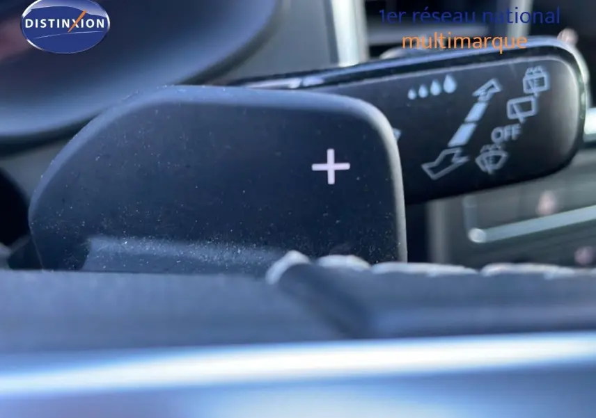 Gros plan sur la palette de changement de vitesse "+" et le commodo de lève-glace dans l'habitacle d'un SEAT Ateca argent.