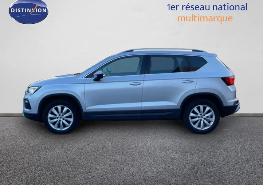 Vue de profil côté gauche d'un SEAT Ateca 2022 argent Reflex Metal avec jantes alliage et barres de toit.