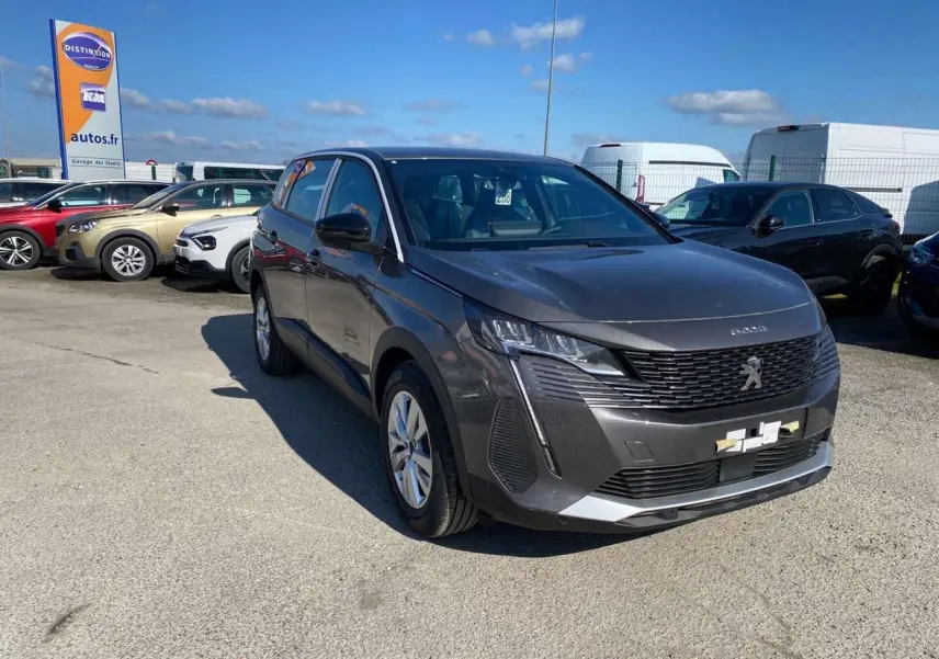 Peugeot 5008 gris platinium métal vue 3/4 avant droit sur parking sous ciel bleu.