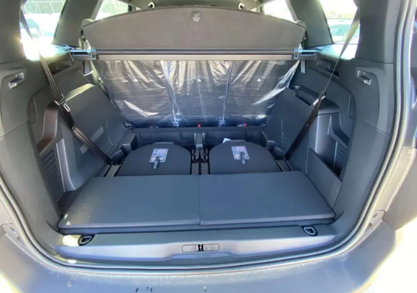 Coffre ouvert vu de l'arrière du Peugeot 5008 gris platinium avec banquette arrière partiellement rabattue.