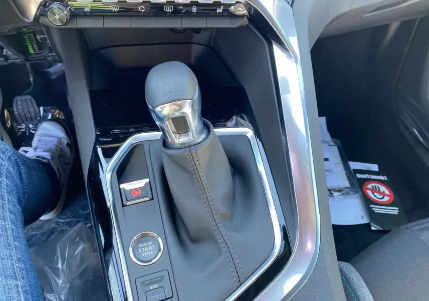 Gros plan sur la console centrale du Peugeot 5008 gris platinium, avec levier de vitesses manuel et bouton start/stop.