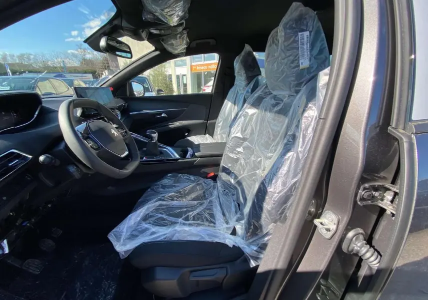 Vue intérieure côté conducteur du Peugeot 5008 gris platinium, sièges avant protégés par housses plastiques.