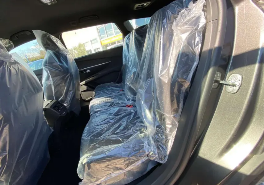 Vue intérieure côté droit des sièges arrière du Peugeot 5008 gris platinium métallisé, protégés par des housses plastiques.