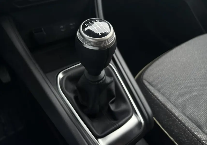 Le levier de vitesse manuel noir avec pommeau argenté et coutures visibles dans l'habitacle du Renault Captur TCE 100 Techno.