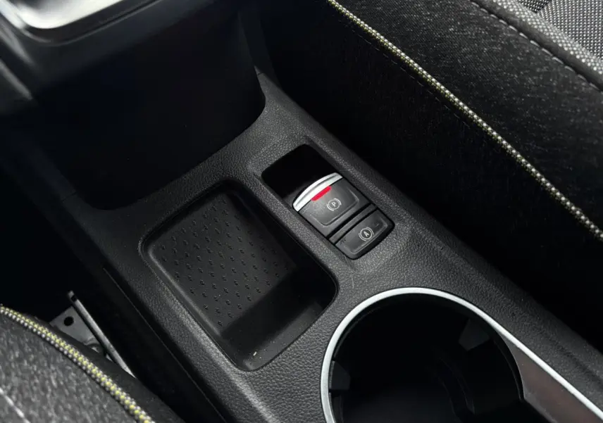 Gros plan sur la console centrale du Renault Captur TCE 100 Techno 2025, montrant frein à main électrique et rangement noir.
