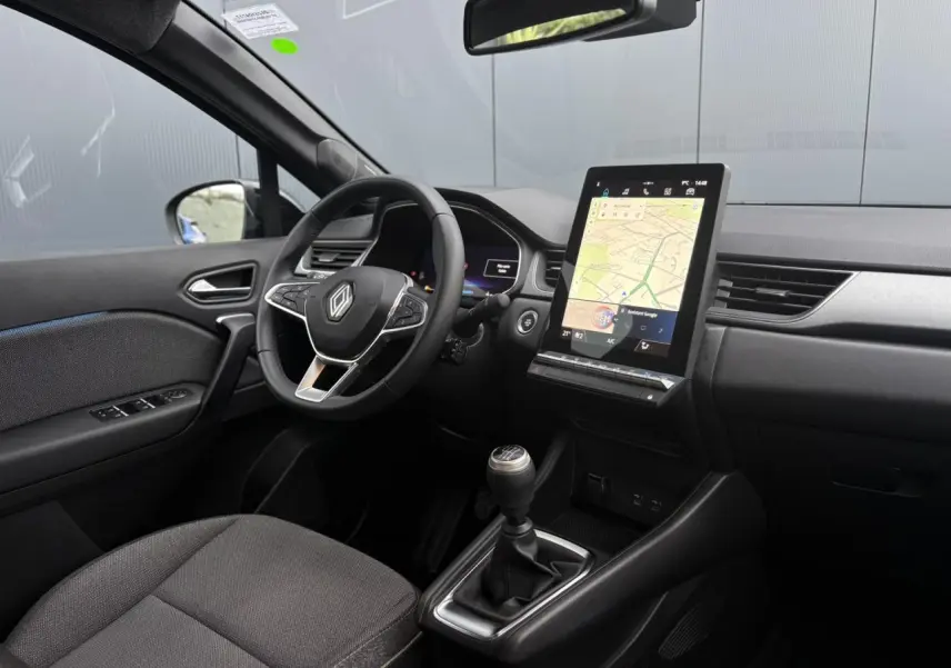 Intérieur avant du Renault Captur TCE 100 Techno 2025, vue côté conducteur, tableau de bord numérique et écran tactile GPS vertical.