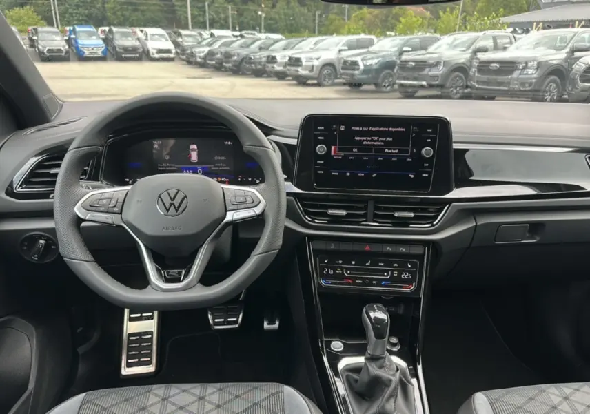 Vue intérieure du tableau de bord et volant du Volkswagen T-Roc gris pyrite 2025 en version R-Line Black.