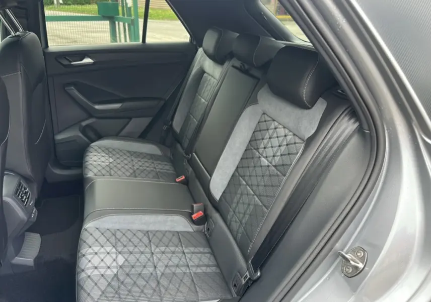 Vue intérieure arrière droite du Volkswagen T-Roc 2025 gris pyrite, sièges arrière en tissu et cuir avec surpiqûres contrastées.