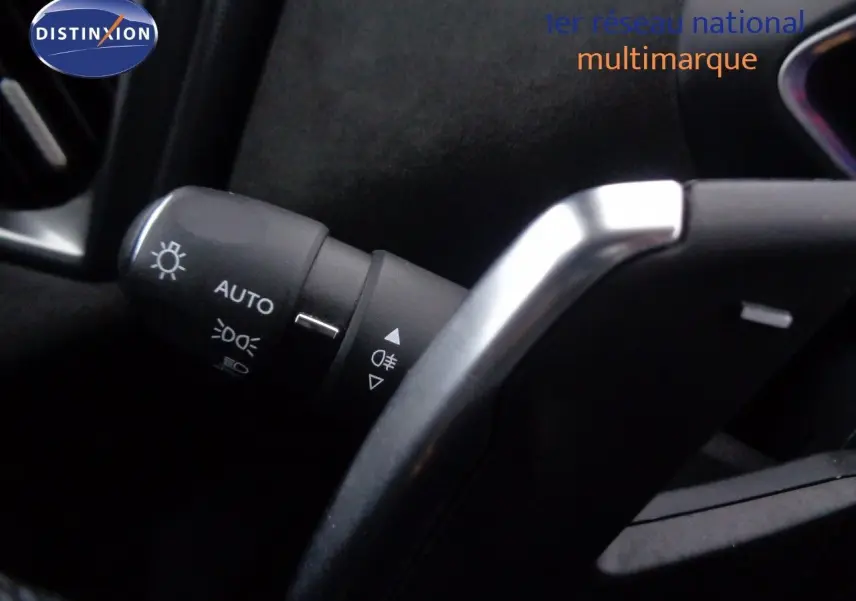 Gros plan sur la commande des feux automatiques et le volant partiellement visible d’un DS3 Crossback blanc banquise.