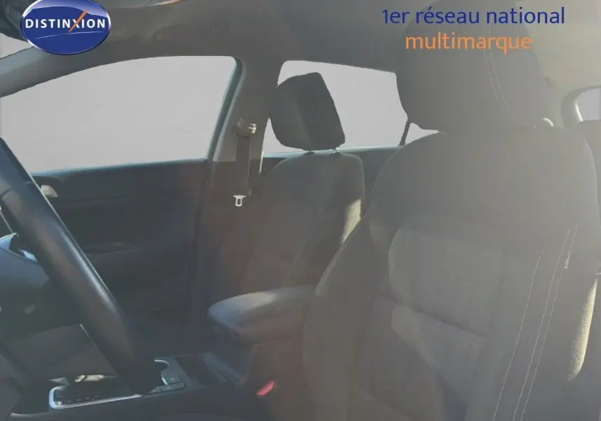 Vue intérieure montrant les sièges avant en tissu noir du Kia Sportage 2021, avec accoudoir central et volant partiel visible.