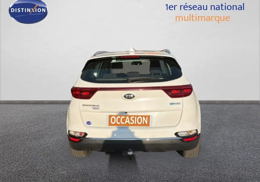 Vue arrière d'un Kia Sportage blanc nacré métal 2021 avec attelage et feux LED visibles.