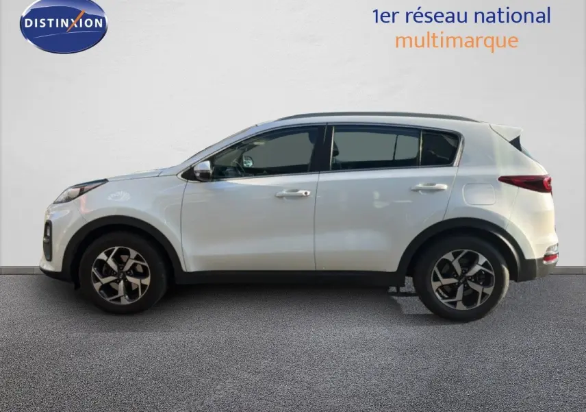 Vue de profil côté gauche d'un Kia Sportage blanc nacré métal, avec jantes bi-ton et vitres teintées.