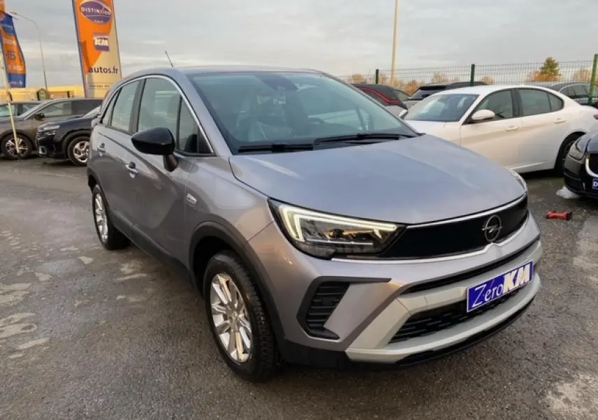 Opel Crossland gris alu en 3/4 avant droit, avec coques de rétroviseurs noires et jantes alliage 16 pouces.