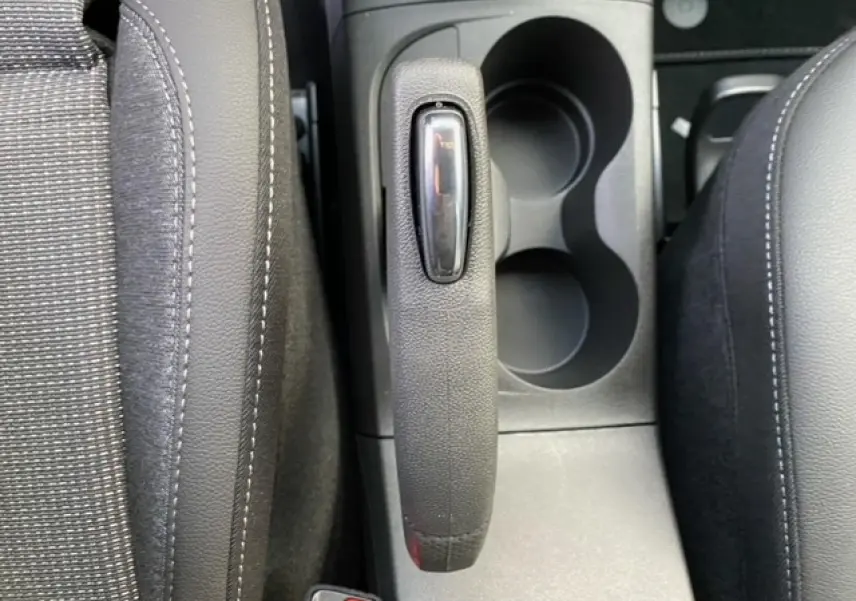 Vue plongeante sur le frein à main et porte-gobelets entre les sièges avant noirs de l’Opel Crossland gris alu.