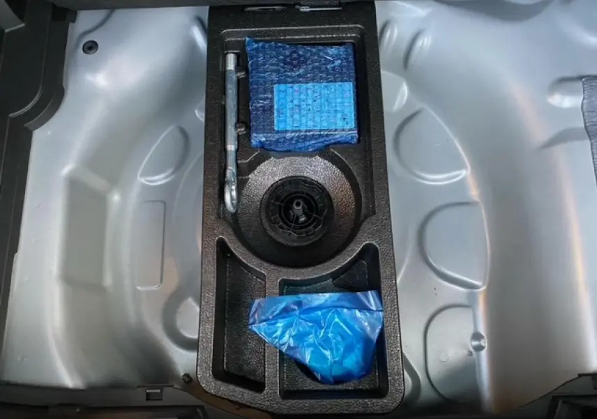 Coffre ouvert de l’Opel Crossland gris alu 2022, montrant le rangement sous plancher avec outils et accessoires en mousse noire.