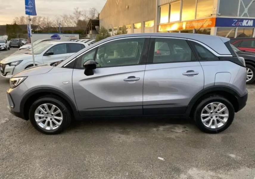 Vue de profil côté gauche d’un Opel Crossland gris alu 2022 avec coques de rétroviseurs noires et jantes alliage 16 pouces.