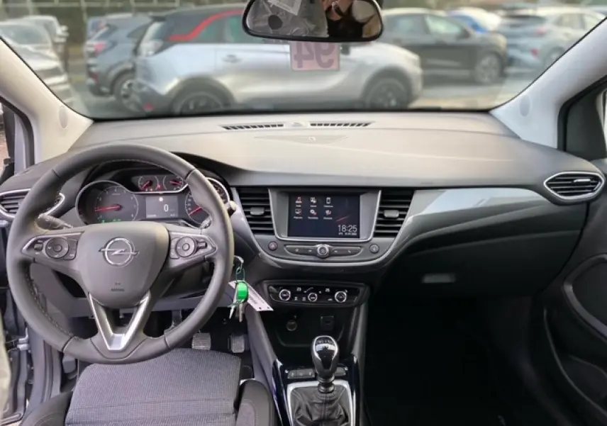 Intérieur Opel Crossland 2022 vu de face, tableau de bord noir avec écran tactile et levier de vitesse manuel.