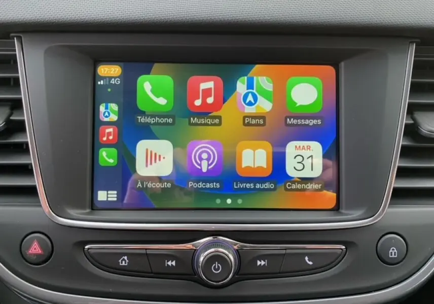 Écran tactile central de l’Opel Crossland 2022 affichant Apple CarPlay avec icônes colorées, entouré de commandes noires.