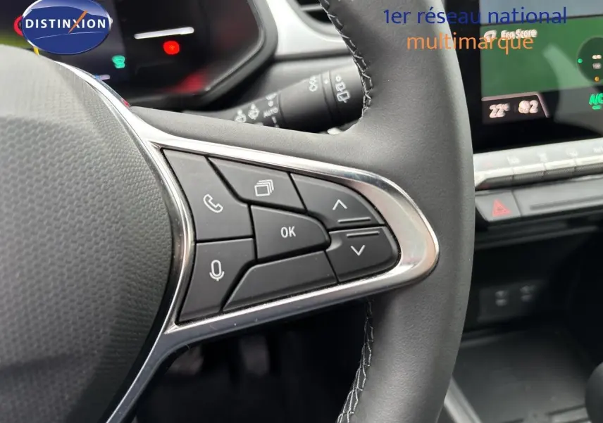 Gros plan sur les commandes multifonctions à droite du volant noir du Renault Symbioz blanc nacré, avec tableau de bord digital en arrière-plan.