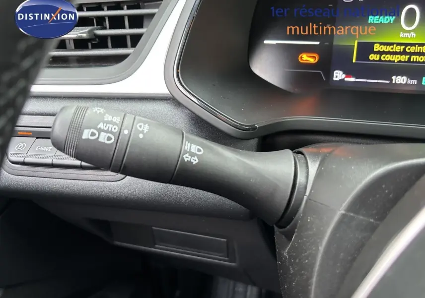 Gros plan sur la commande des feux et clignotants à gauche du volant dans le tableau de bord du Renault Symbioz blanc nacré.